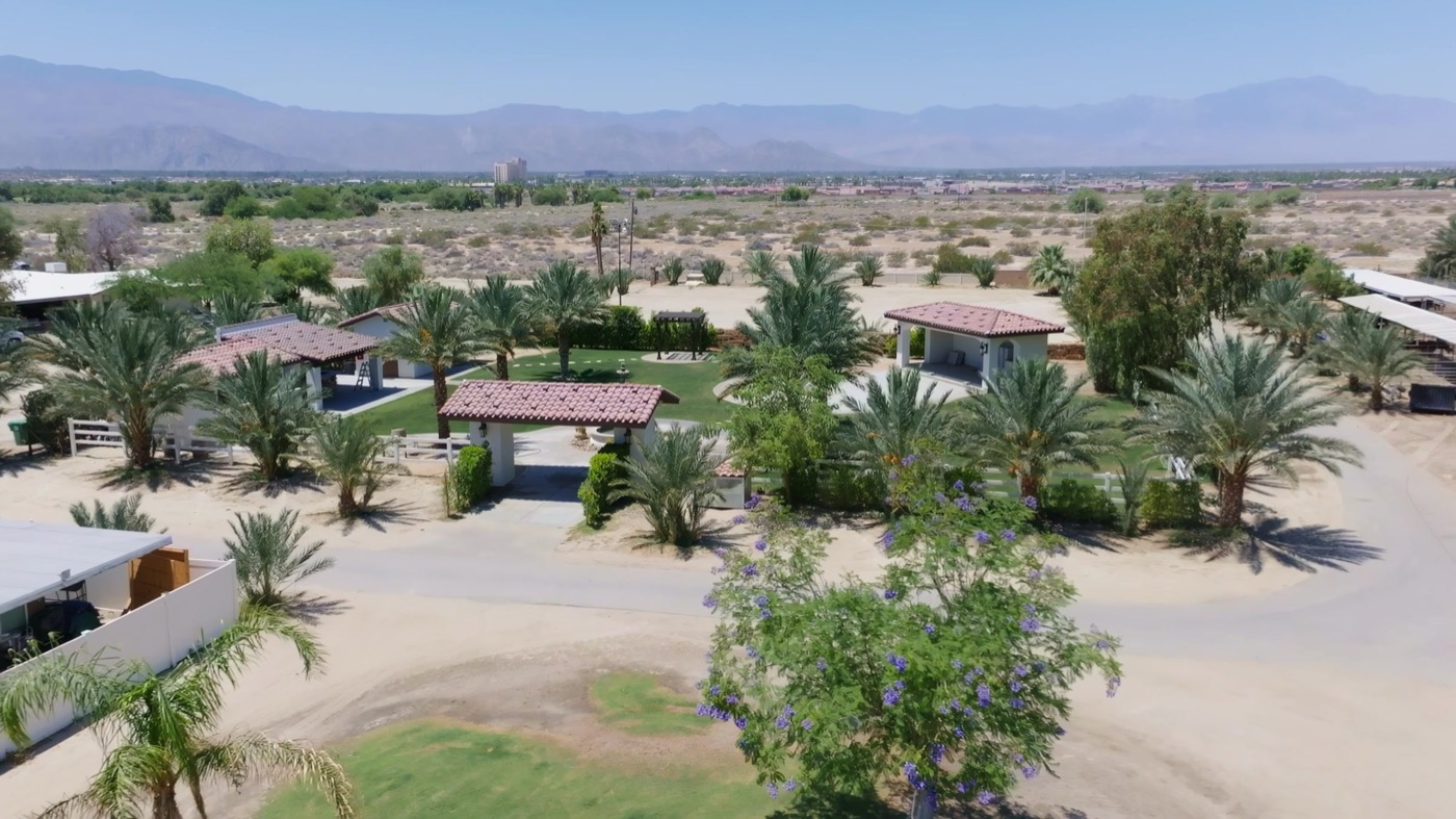 Aerial view of Rancho Escondido in Indio with palm trees and the mountains behind it